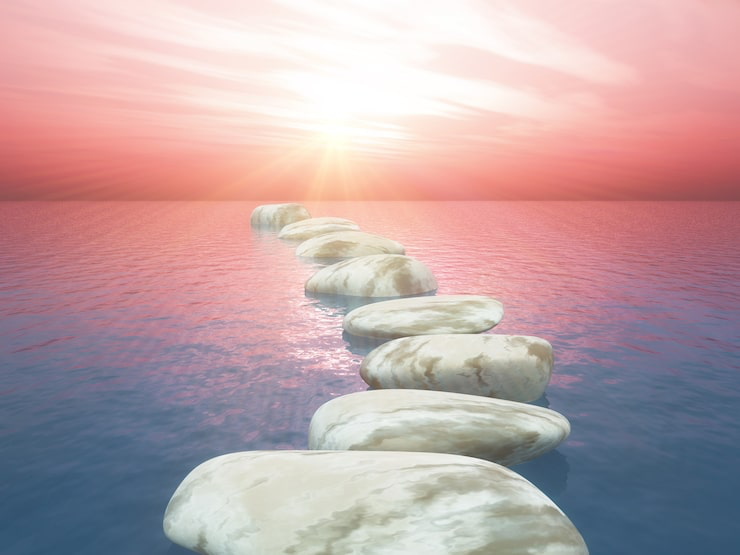 White stepping stones leading across calm water toward warm sunrise light