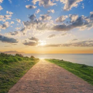 A quiet path leading toward calm water and warm sunset light