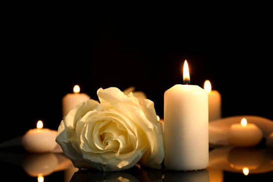 A soft white rose beside gently glowing candles